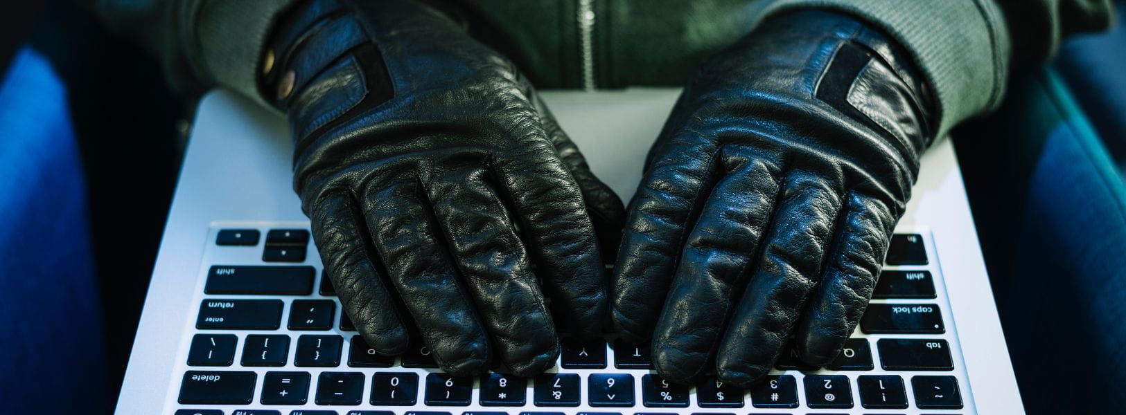 Hacker v kožených rukavicích píše na klávesnici